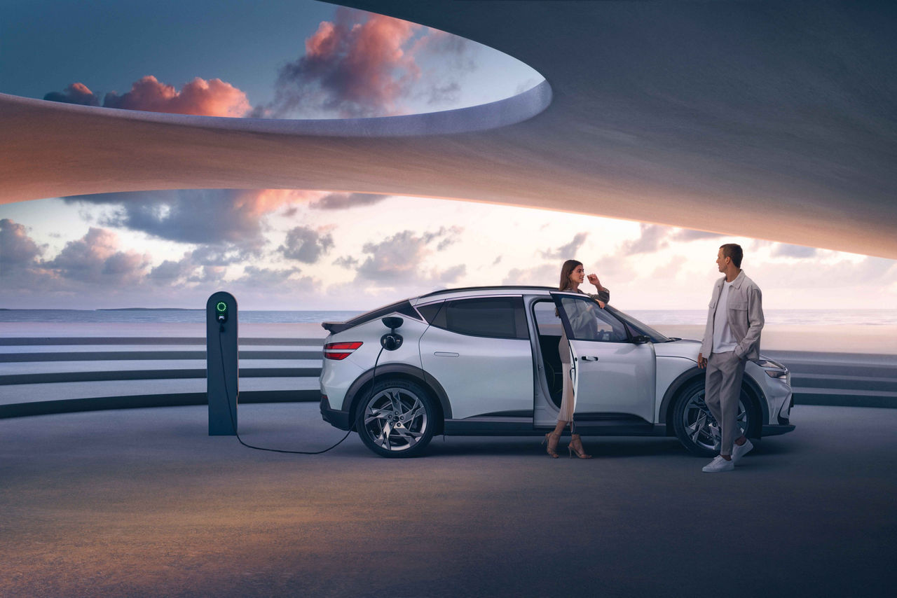 Man and woman next to an electric car parked at a charging station by the sea