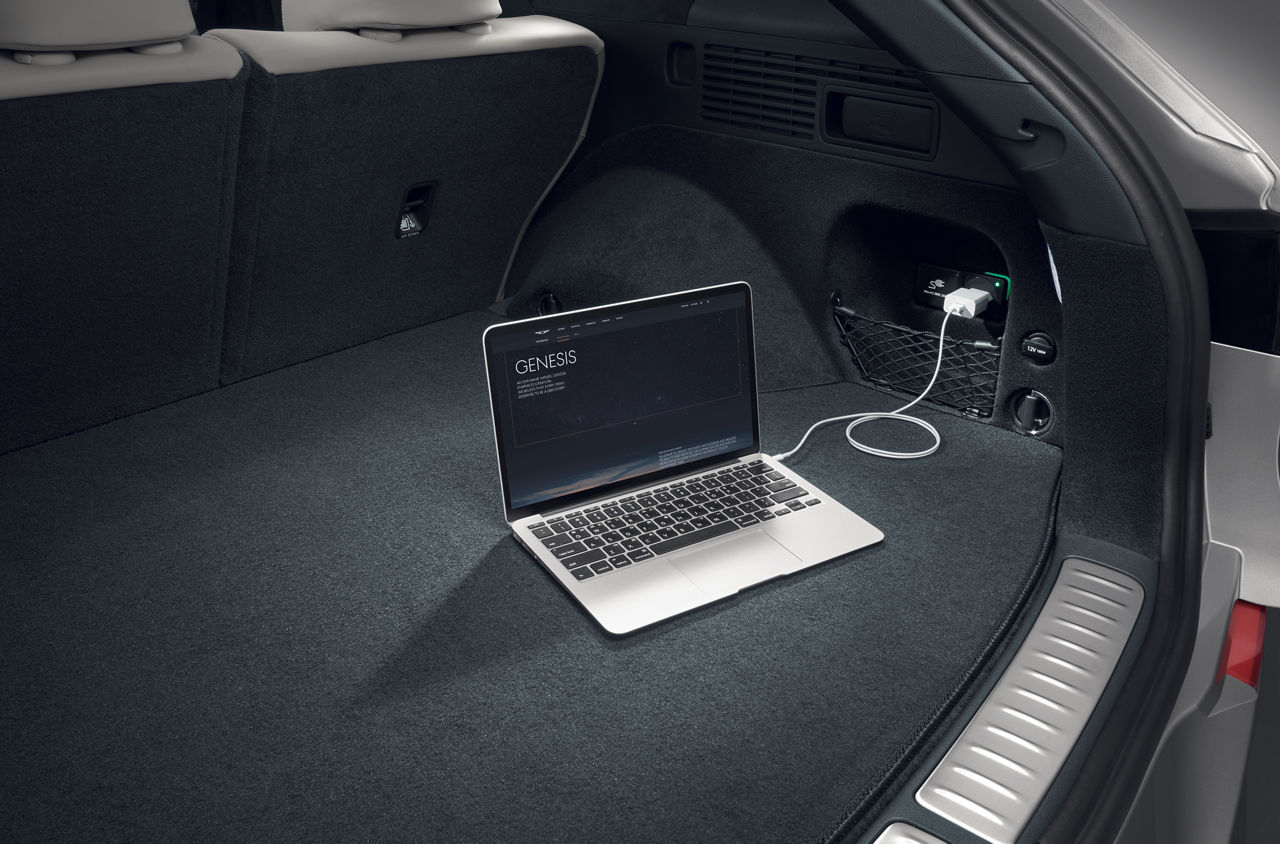 Laptop am Stromanschluss im Kofferraum eines Autos