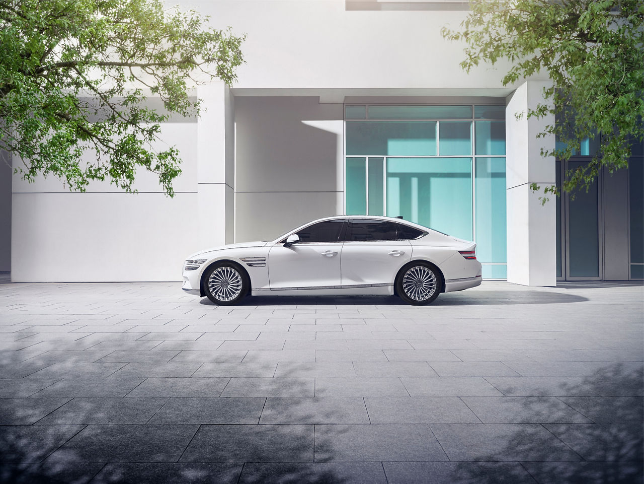 White Genesis G80 from the side in front of a building