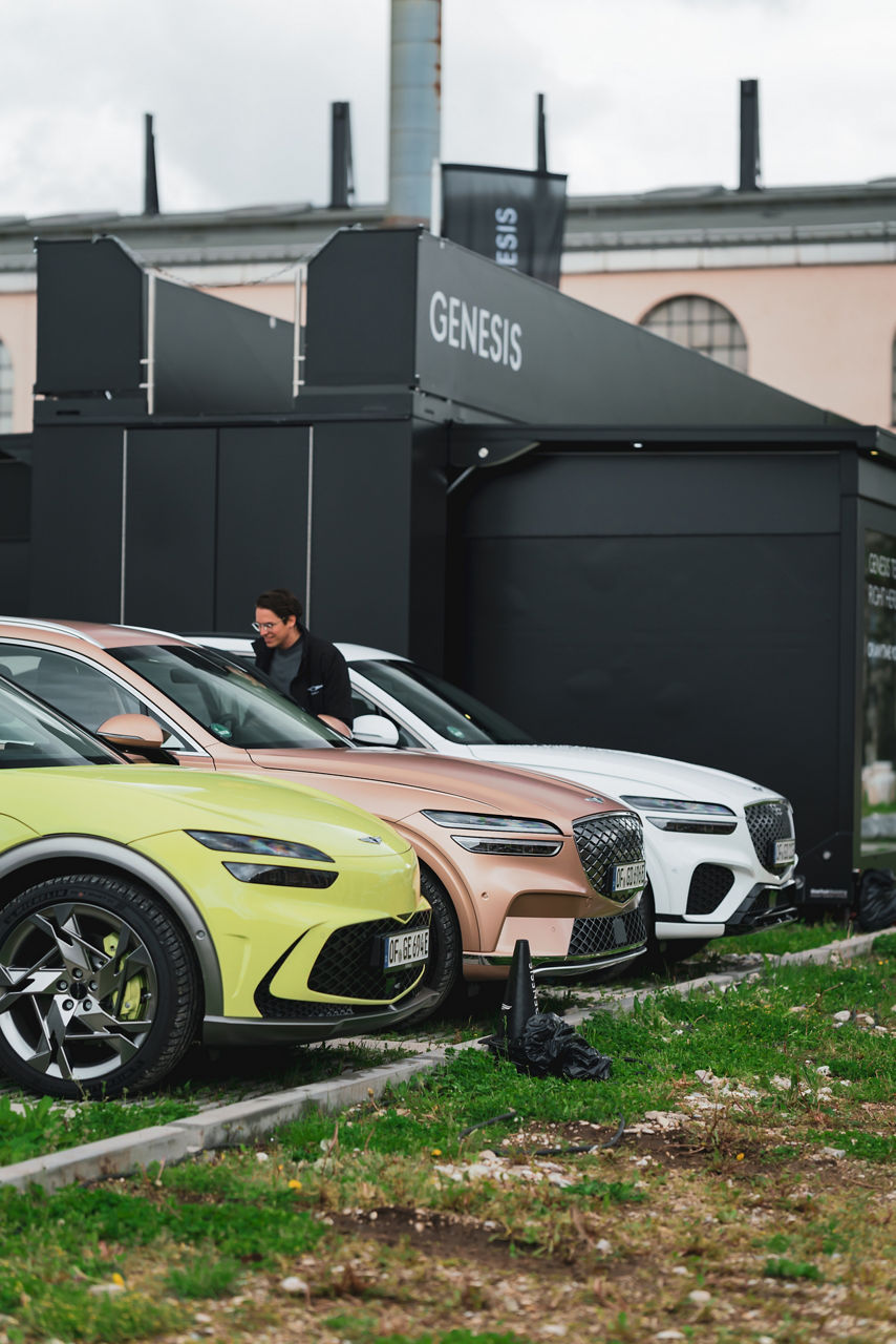 Car park with three Genesis cars in lime, copper and white