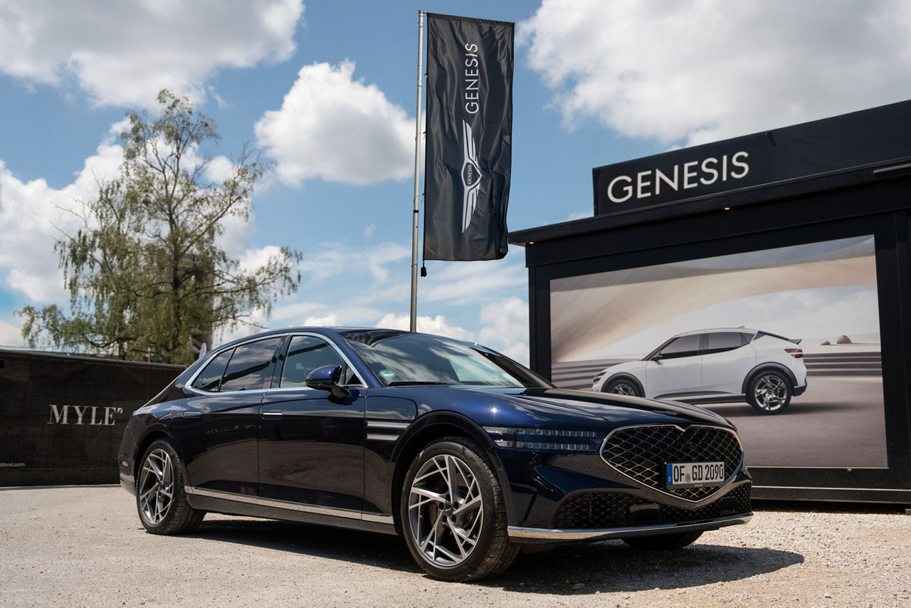 Genesis G80 in front of a GV60 poster on the Myle festival