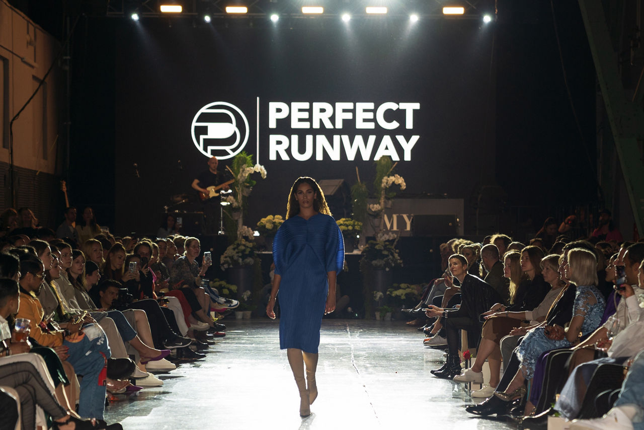 Woman on a catwalk between many people