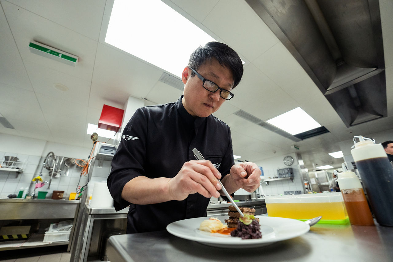Chef in kitchen prepares the food on the plate