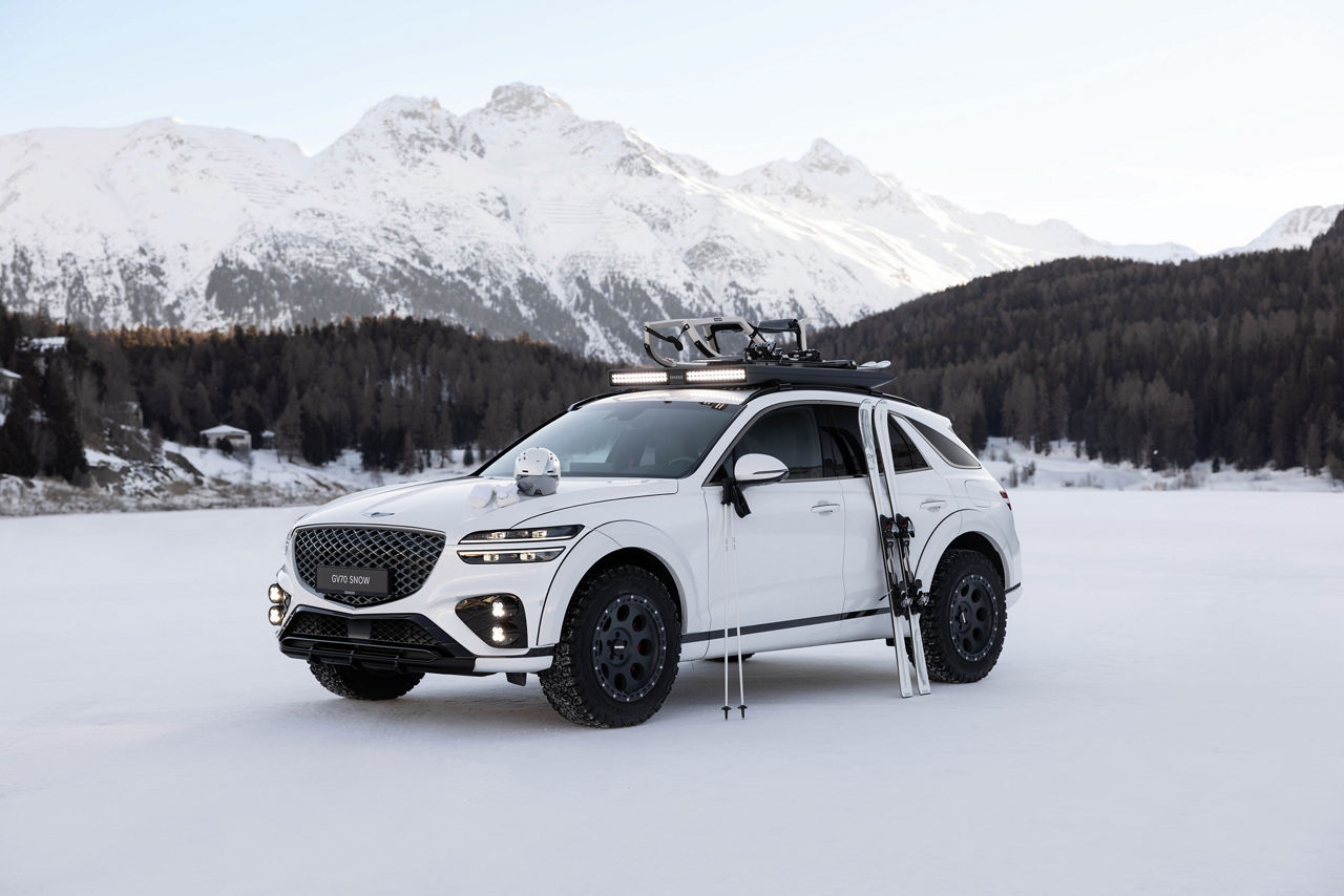White Genesis GV70 Snow Concept on snow with ski equipment in front of snow-covered mountains