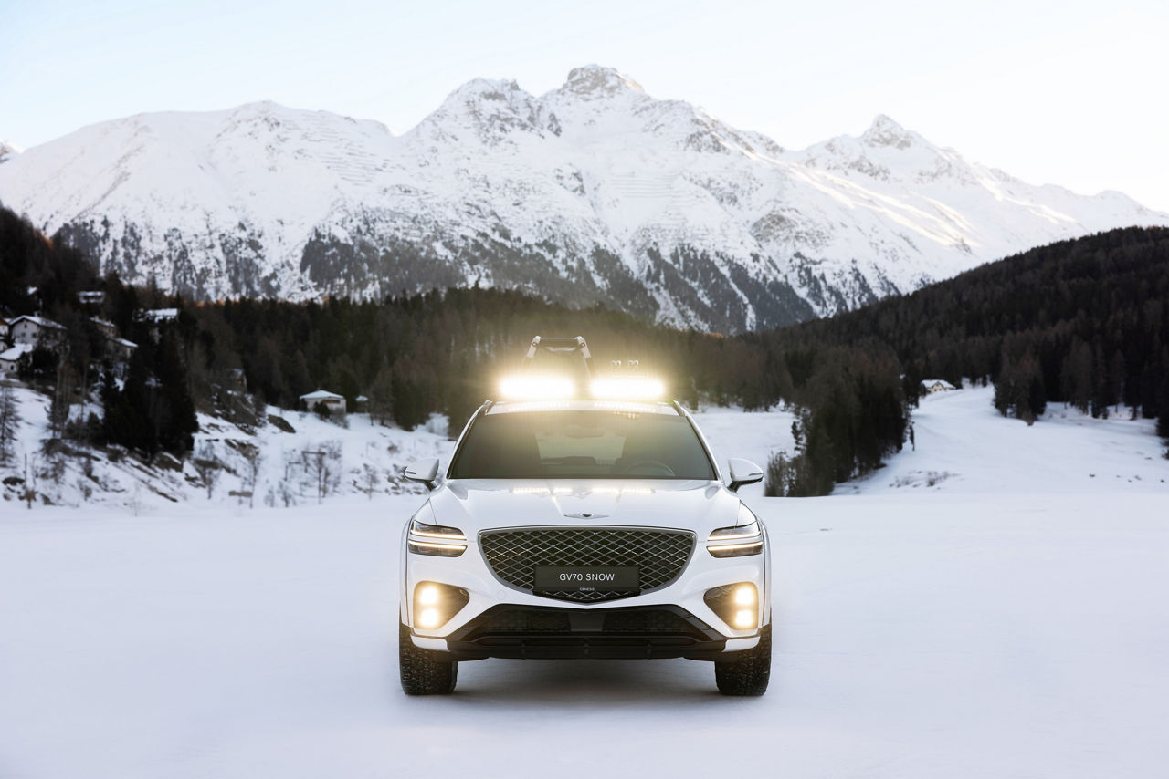 Genesis GV70 Snow Concept white on snow Front view in front of snow-covered mountains