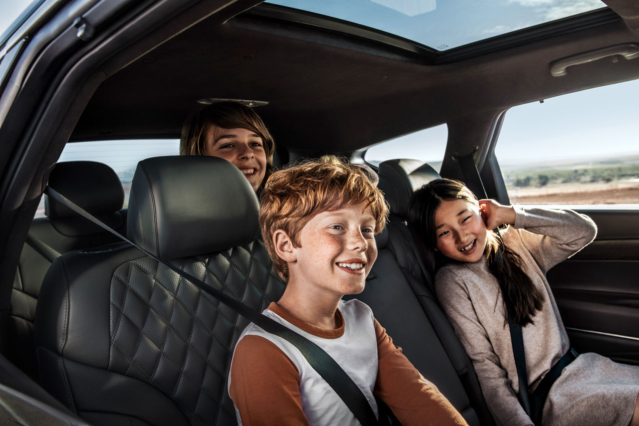 Junge und Mädchen lachen auf den Vordersitzen eines Autos