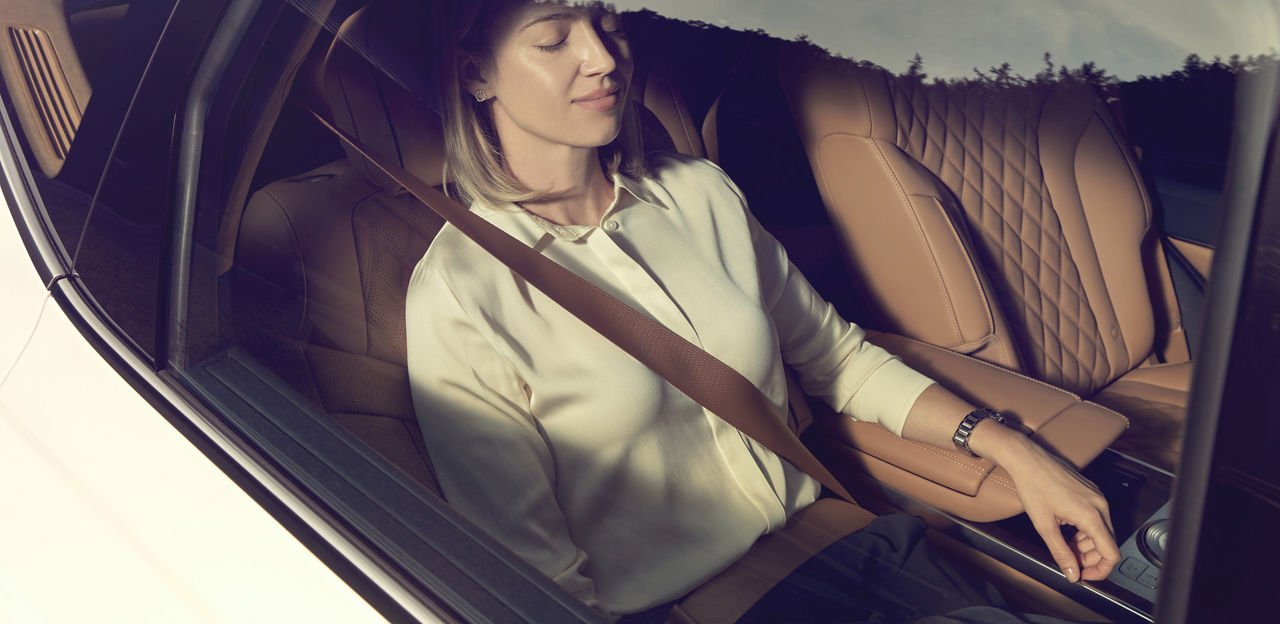 Femme assise à l'arrière d'une voiture, les yeux fermés 