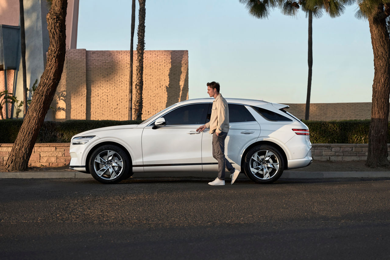 White Genesis GV70 from the side with a man at the driver's door