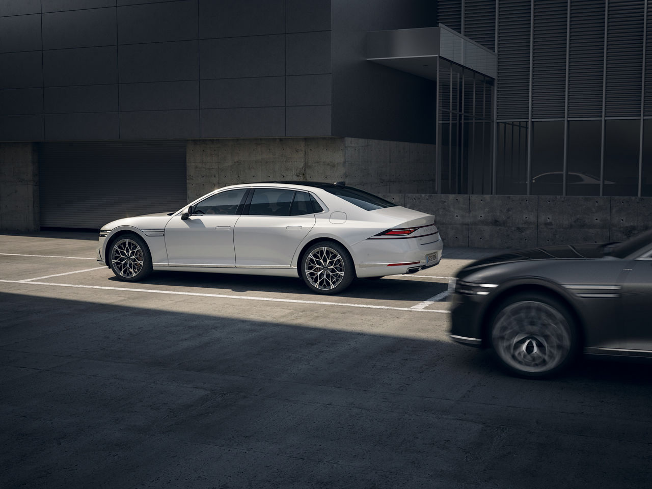 White car parked on a road where a black car is approaching