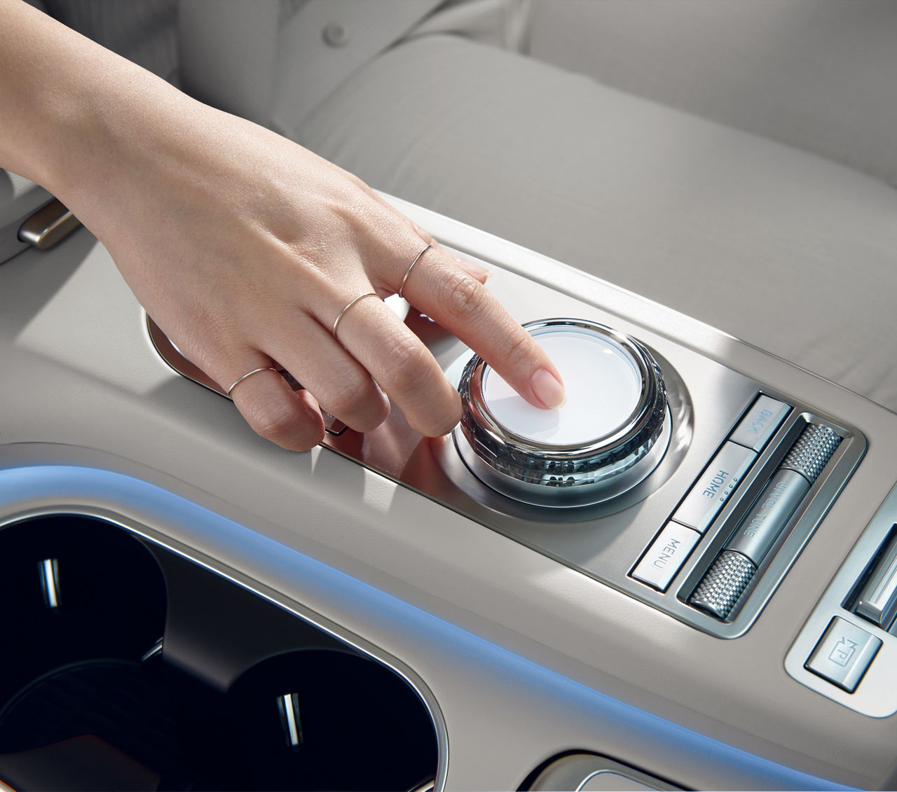 A hand operates a touch controller in the centre console of a car