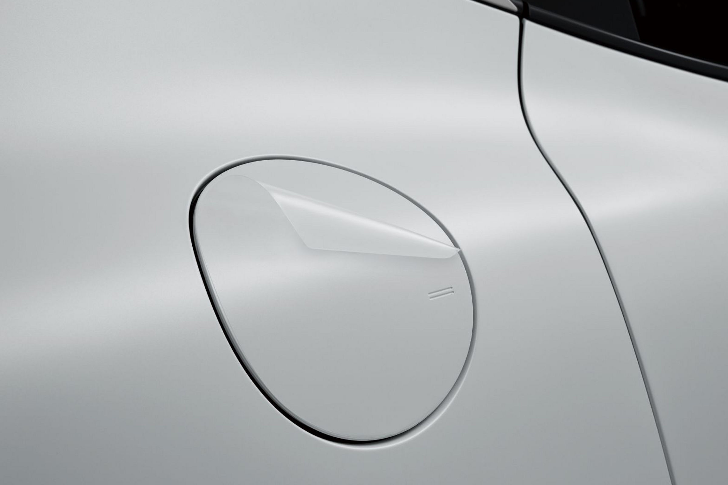 A part of the side of the Uyuni white GV60 vehicle charging port is visible. The film on the vehicle's surface is highlighted.
