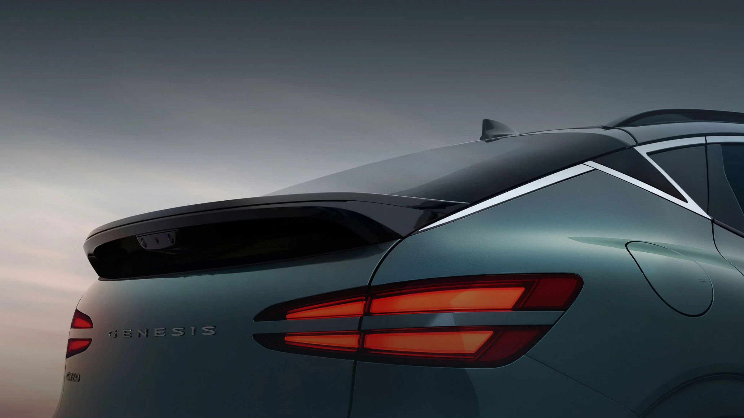  The rear bumper and rear lamp of the Tromso Green GV60 vehicle are visible in the sunset background.