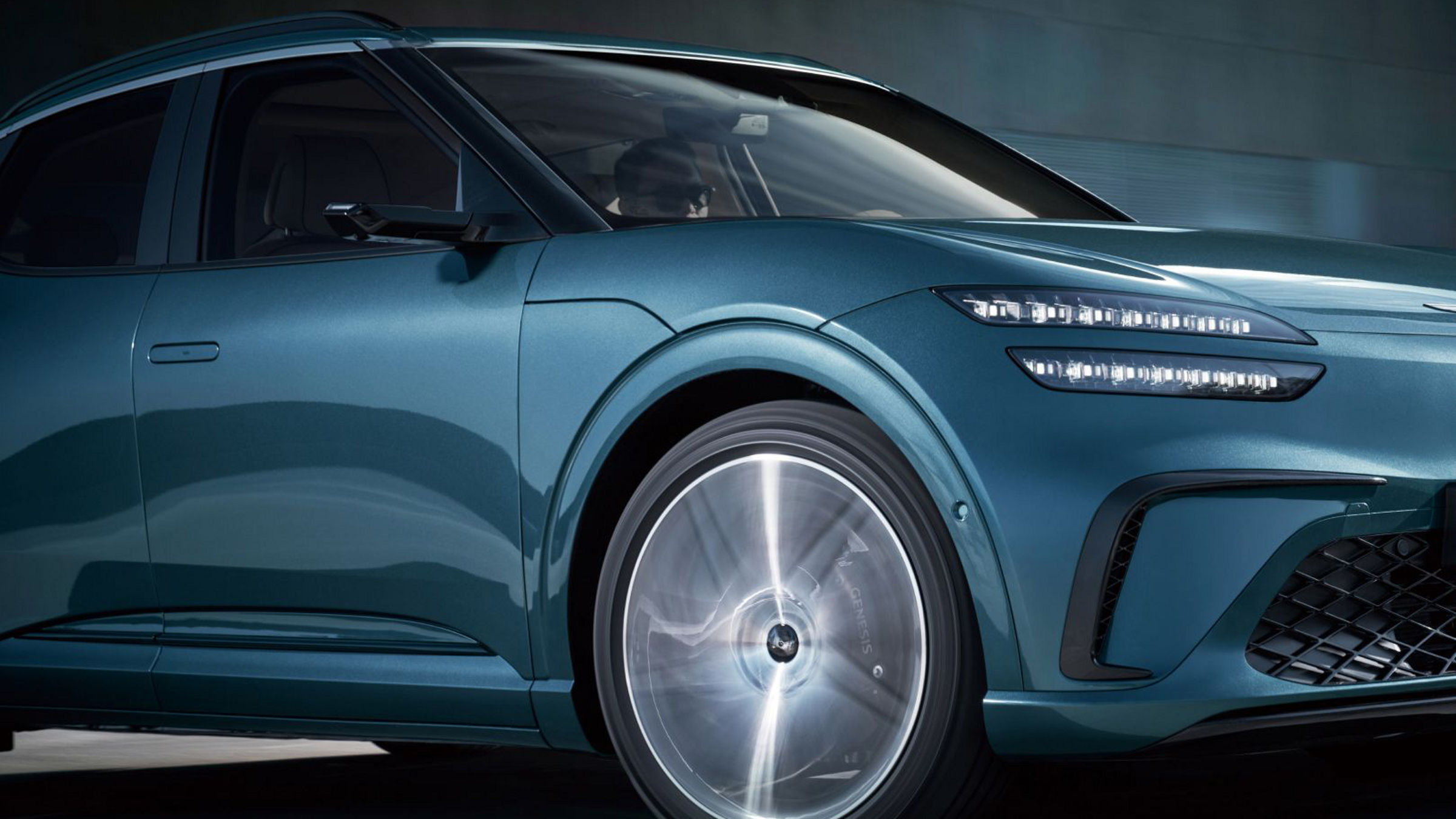 The front wheels of the fast-driving GV60 vehicle are enlarged. You can see the wheel spinning.