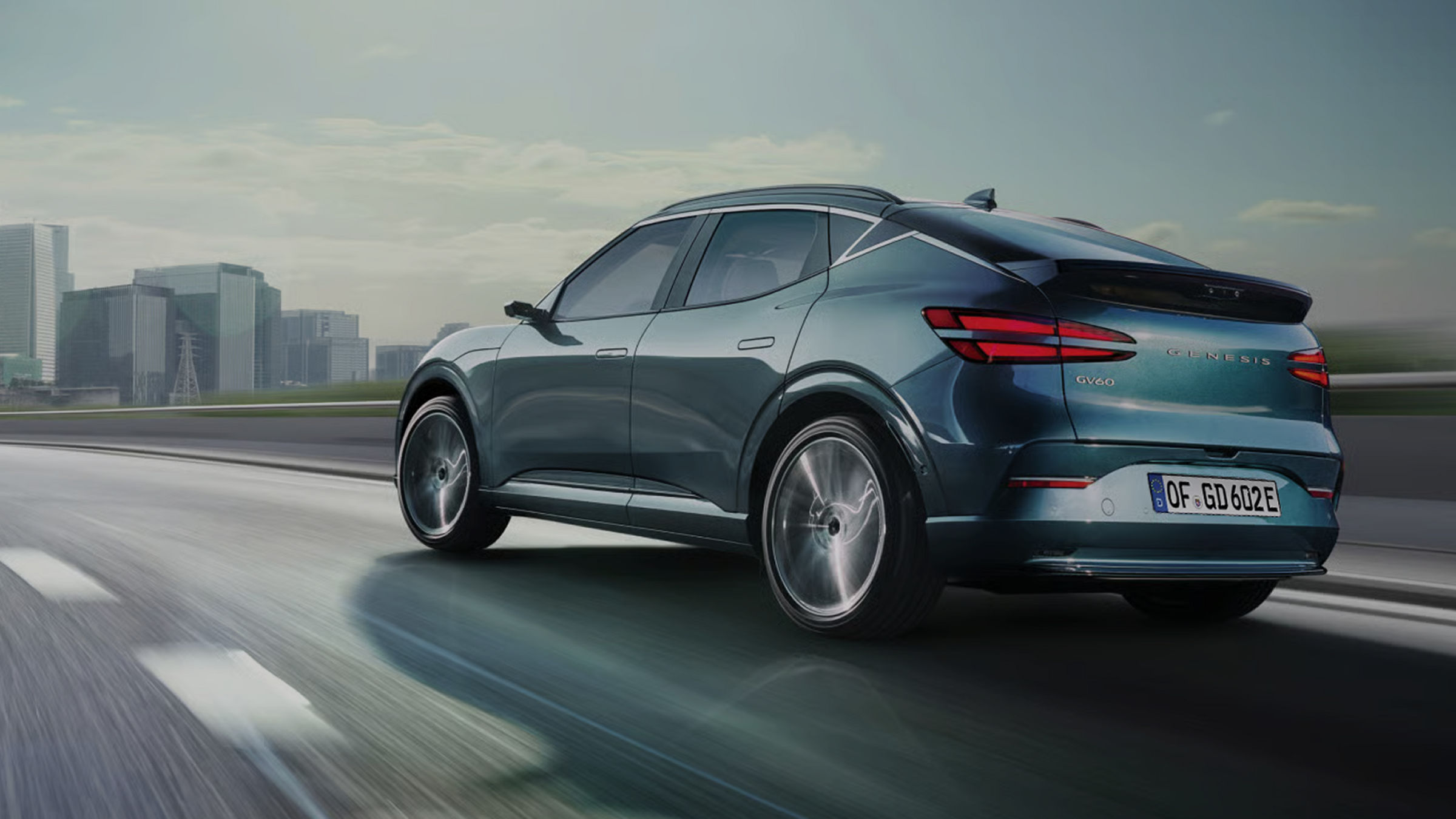 With a modern building in the background, you can see the rear of the GV60 driving fast on the highway.