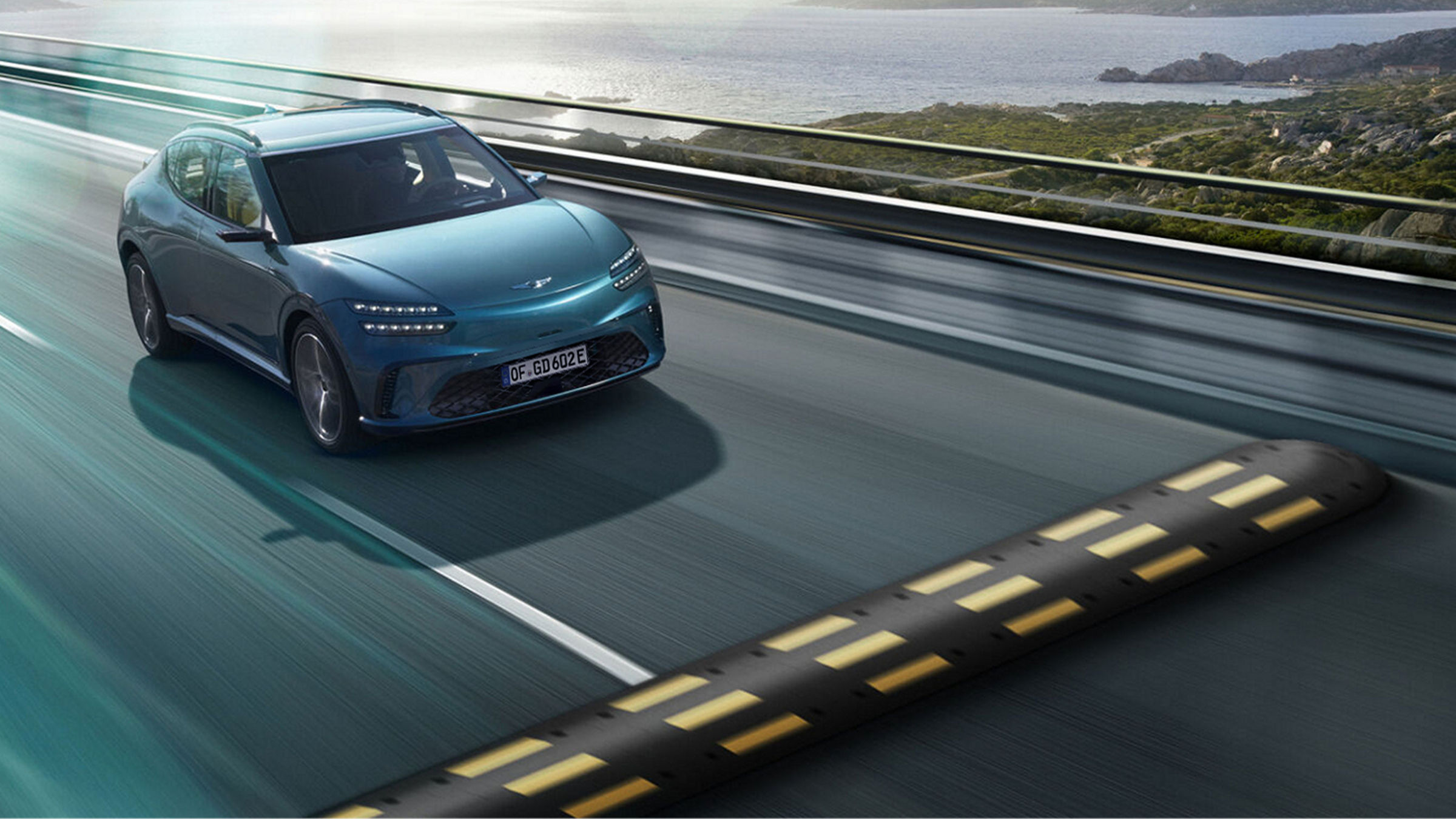  The GV60 vehicle is driving quickly on the road with the natural scenery of the sea and islands in the background. You will see a bump right in front of you.