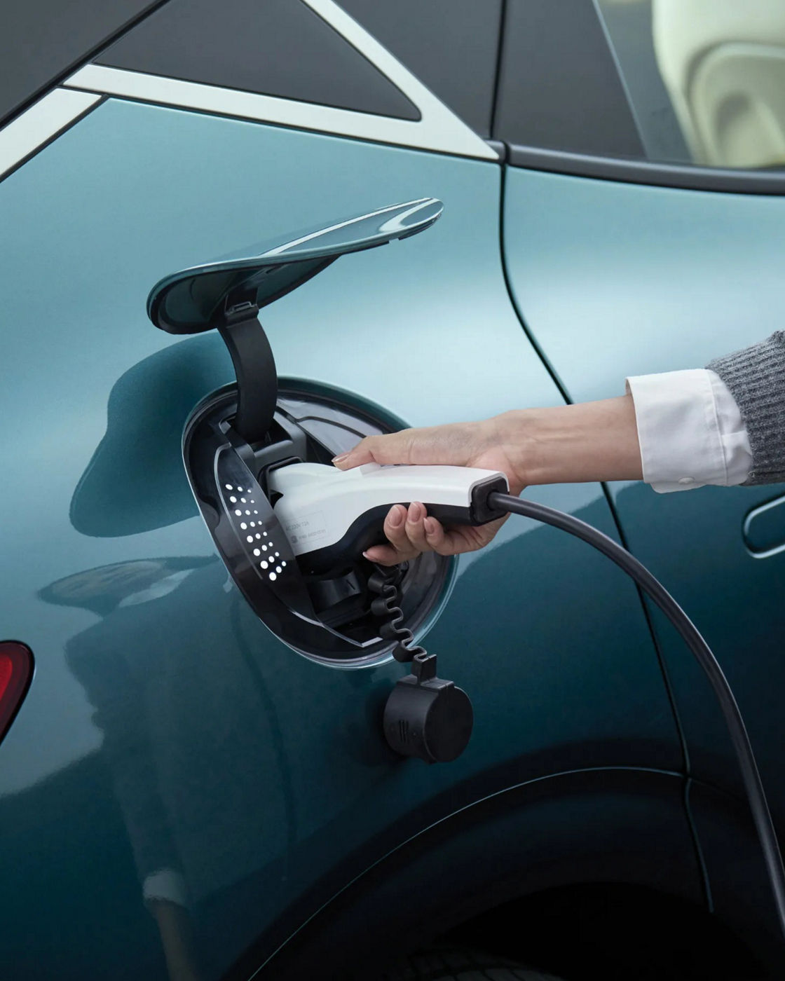 The Genesis car charger is open, and the hands of the person charging it appear to be enlarged.