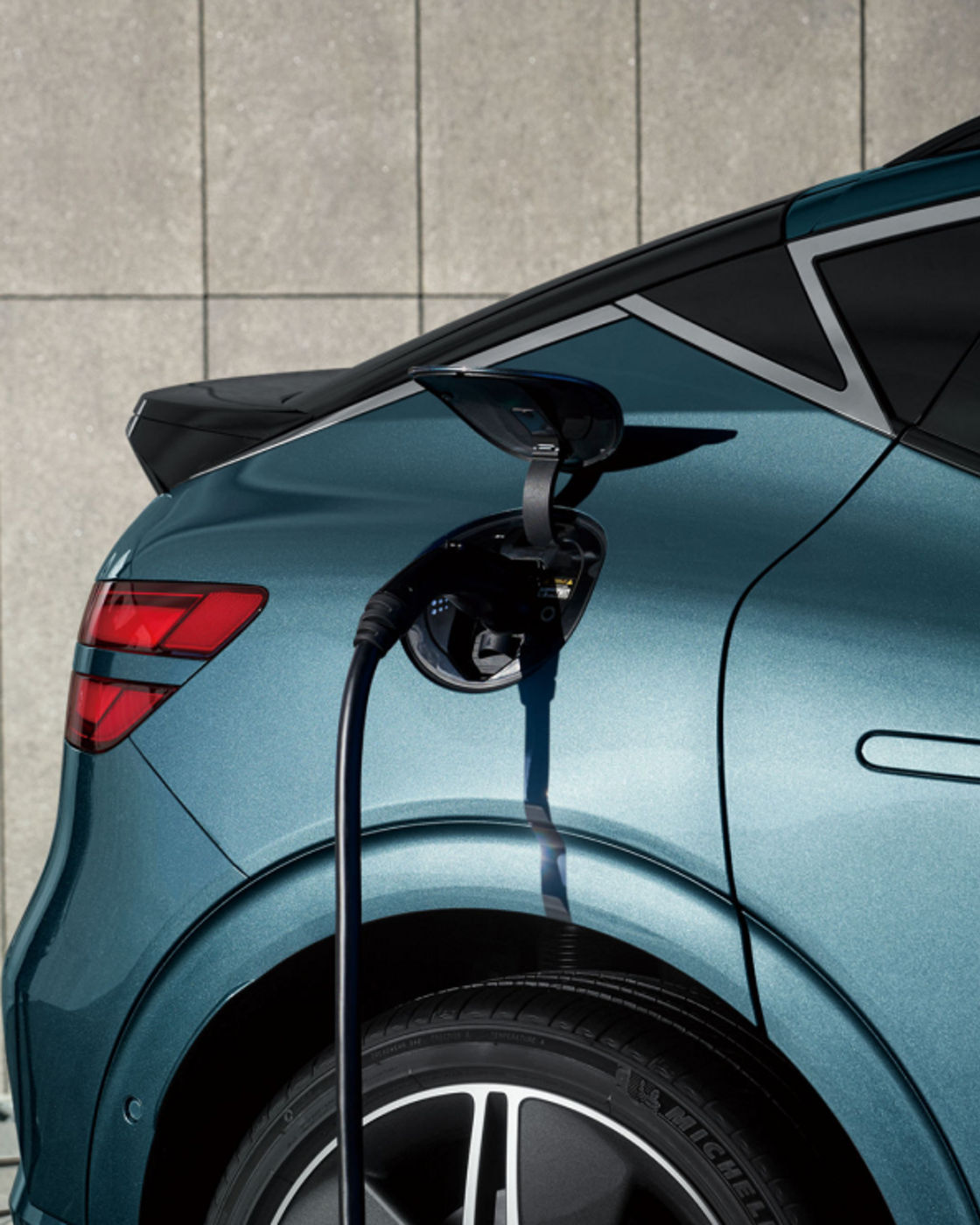 A Genesis EV vehicle is being charged using a Genesis home charger installed on the wall of the building.