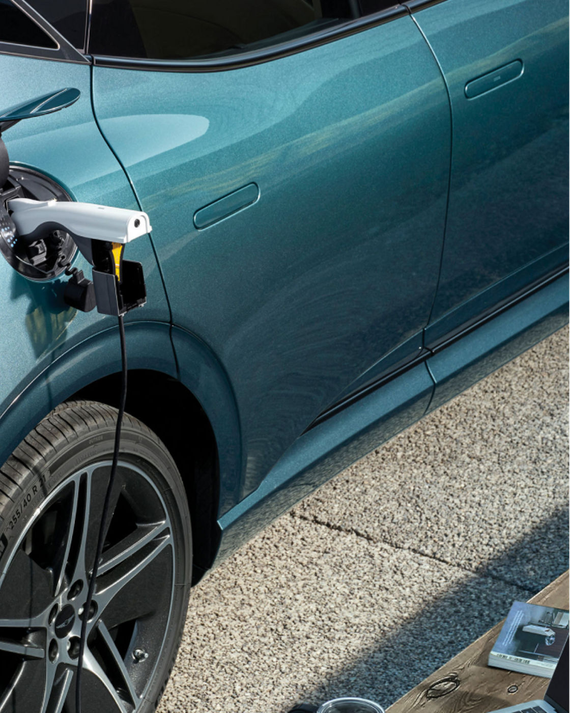 A gender connector connected to the front charging port of the Genesis EV vehicle is connected to the laptop located in front of the vehicle.