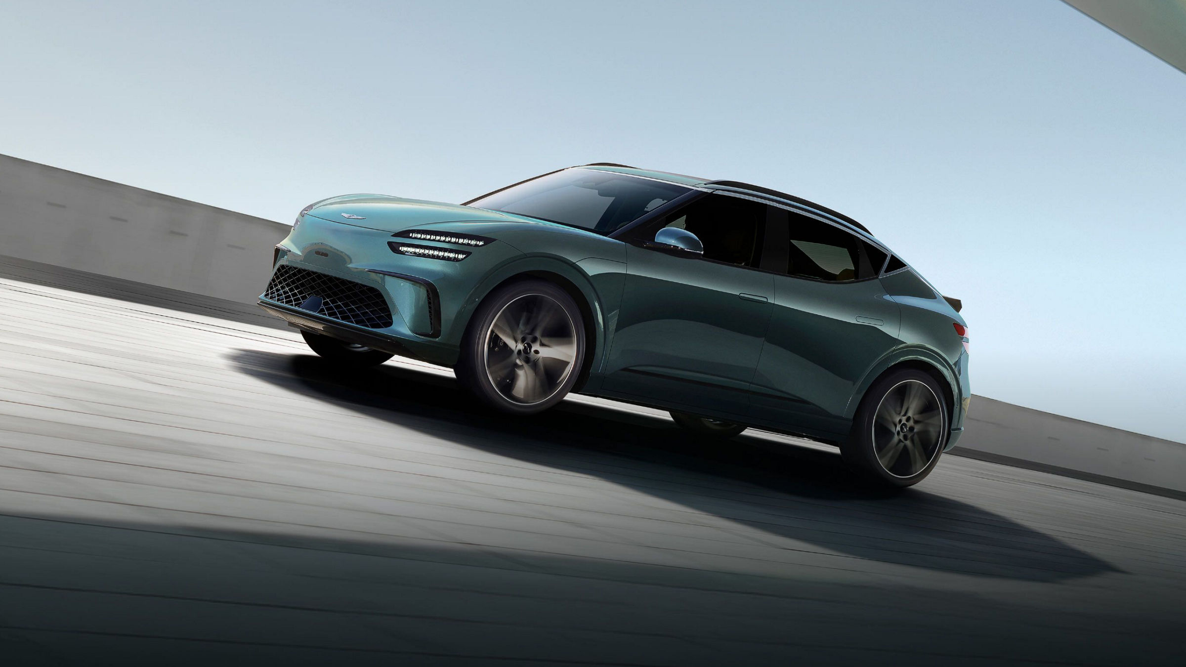 With the blue sky in the background, a Tromso green-colored GV60 is driving toward the side.