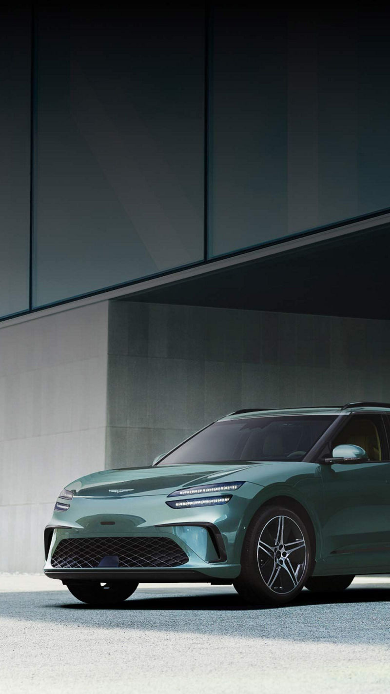  With the modern building in the background, there is a GV60 in Tromso green on the left and a GV60 in Uyuni white on the right.