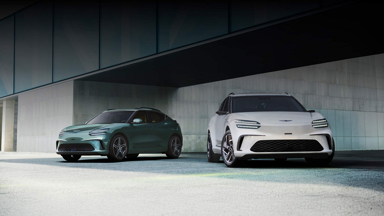  With the modern building in the background, there is a GV60 in Tromso green on the left and a GV60 in Uyuni white on the right.