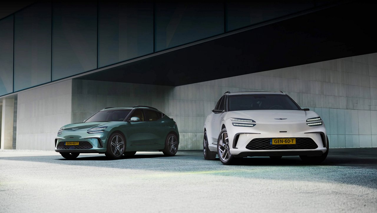 Met het moderne gebouw op de achtergrond staat links een GV60 in Tromso groen en rechts een GV60 in Uyuni wit.