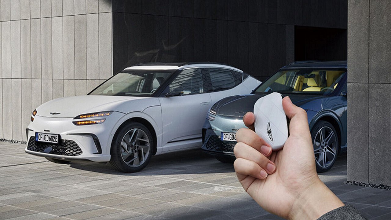 L’immagine mostra il veicolo controllato a distanza dall’esterno tramite la smart key; una mano tiene una smart key bianca.