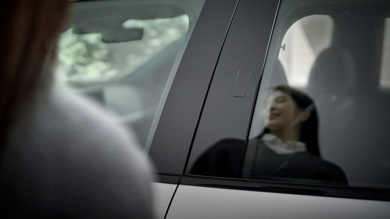 The driver's face can be seen reflected in the rear car window.
