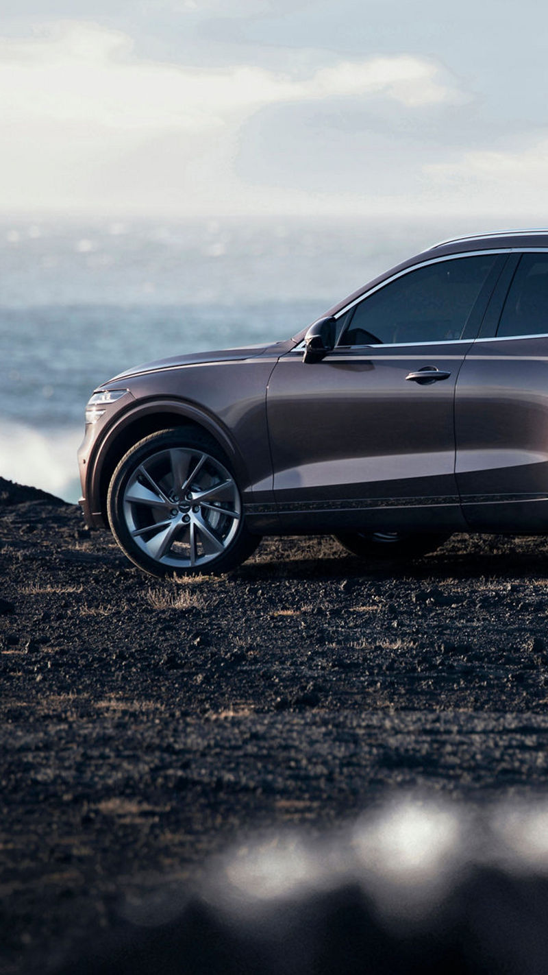 Genesis GV70 parked on a rugged coastal terrain with the ocean in the background, highlighting its elegance and adventurous spirit.