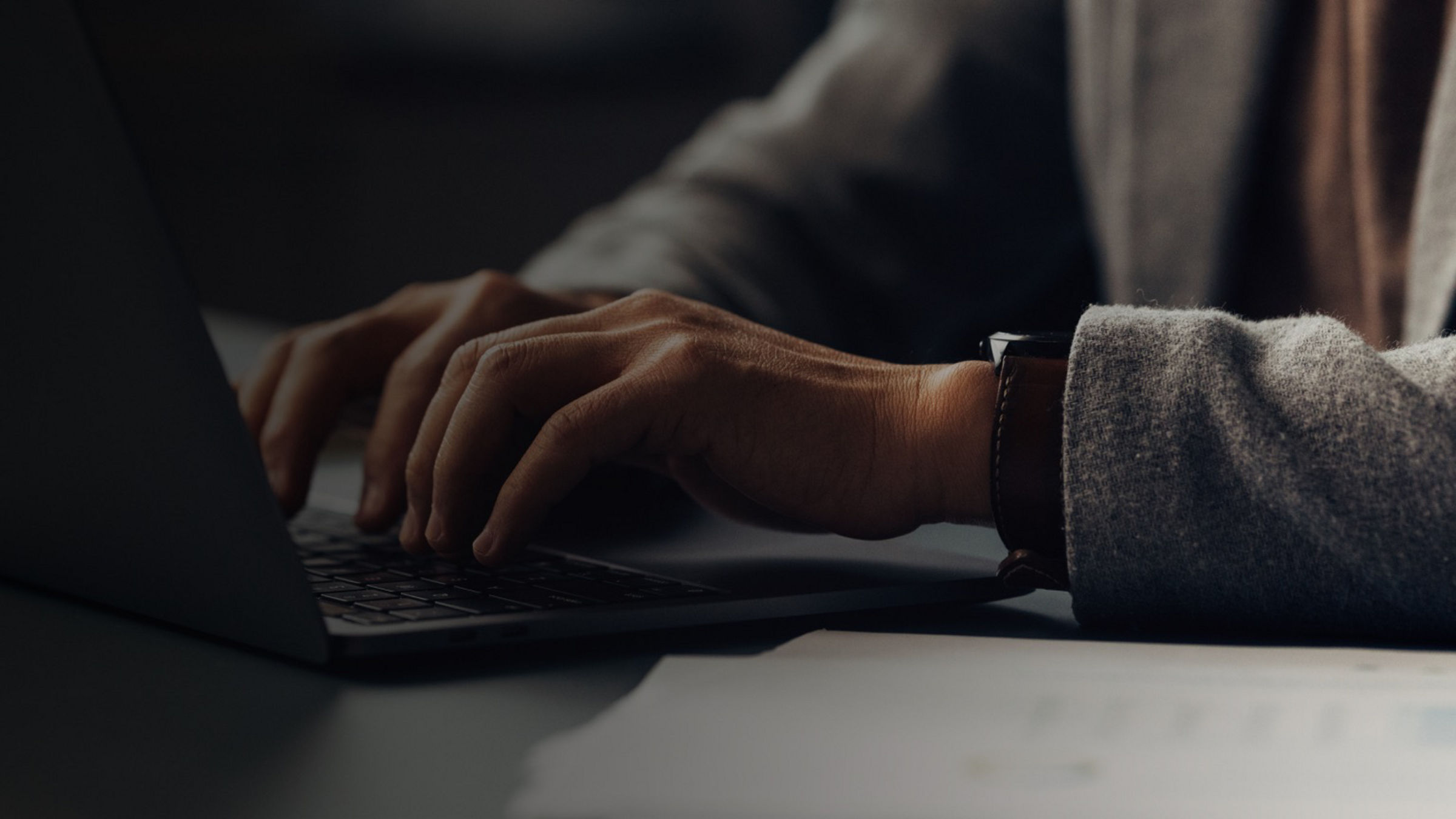 A person typing on a laptop at a desk in a focused work setting