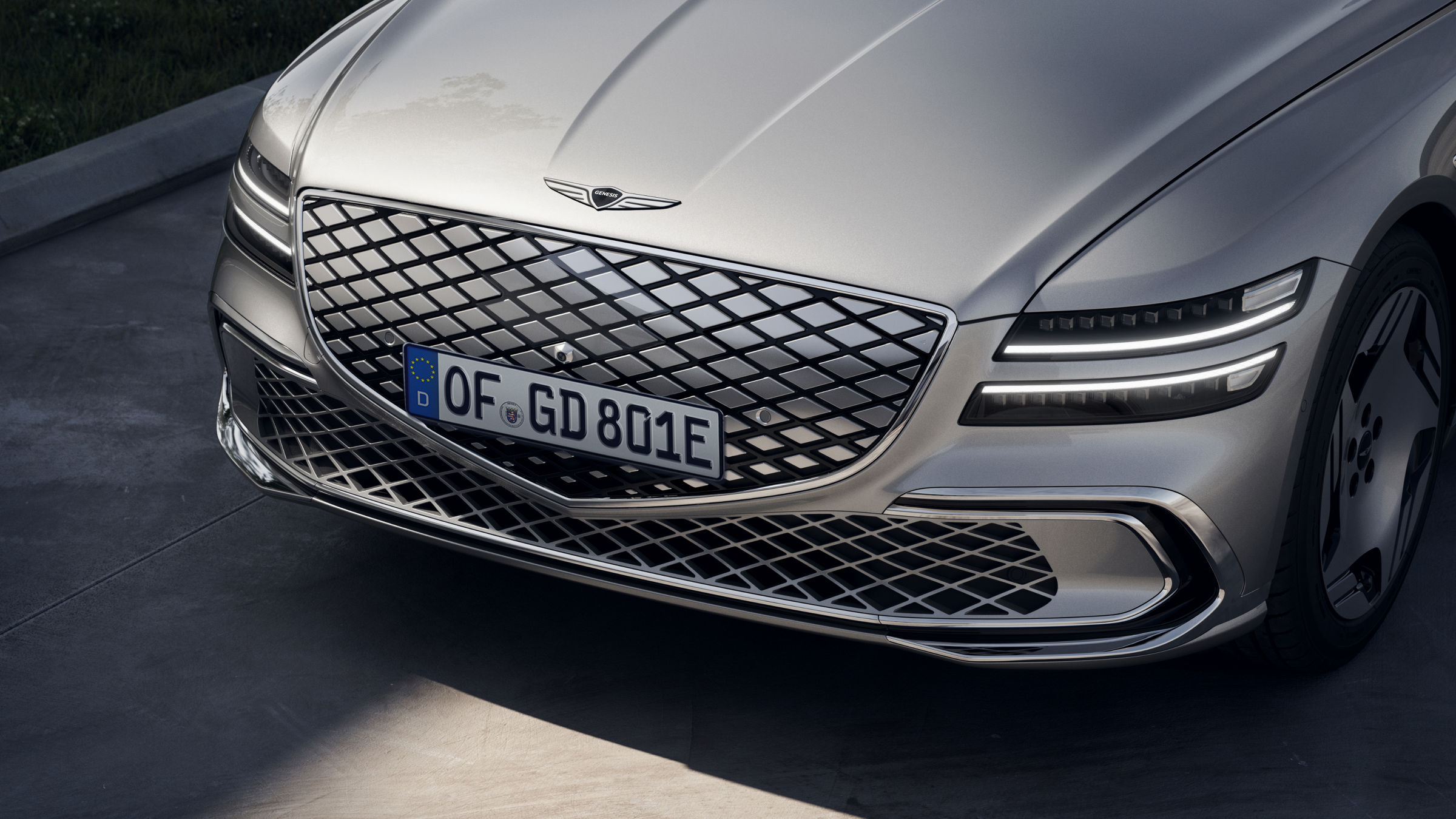 A zoomed-in view of the front headlamps and G-Matrix patterned crest grill of the Electrified G80. 
