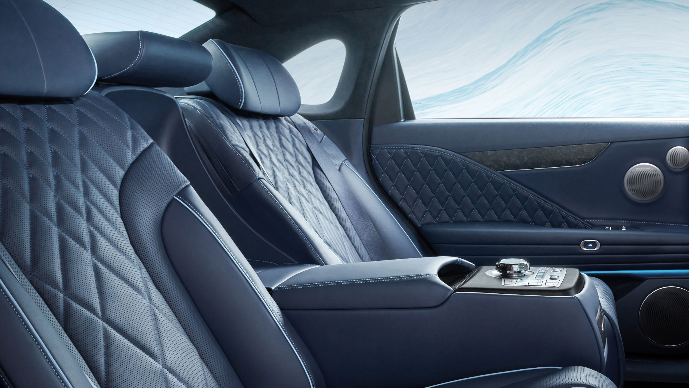 View of the back seat inside the Electrified G80. The quilted seats in a luxurious ecru black monotone and the controller in the center are visible.
