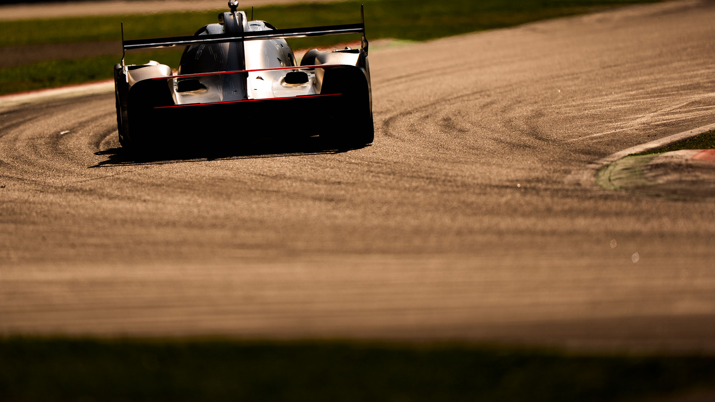 Genesis GRM-001 driving away on curving circuit with tire marks.