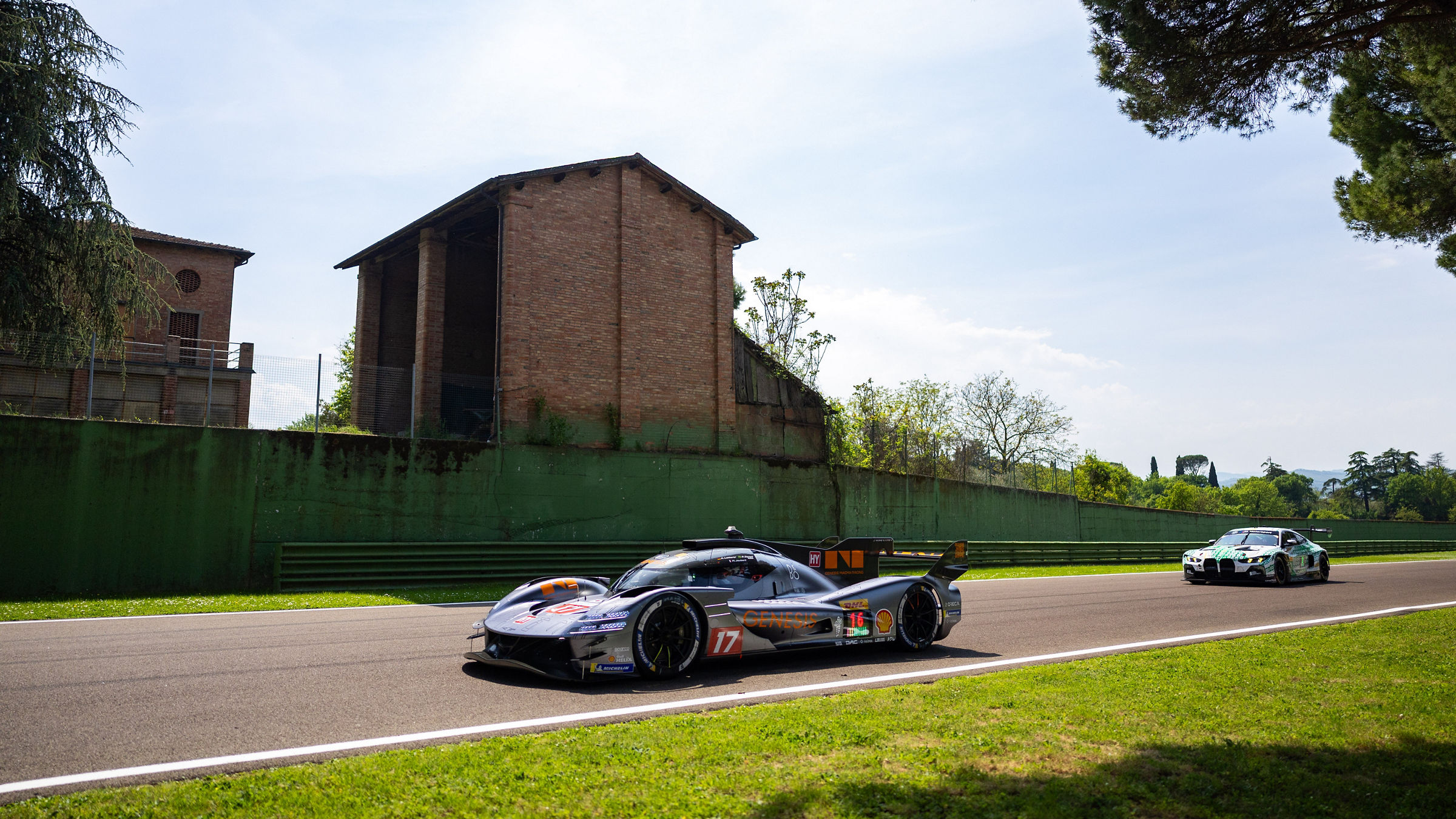 Genesis GRM-001 passing historic brick building on track at Imola.