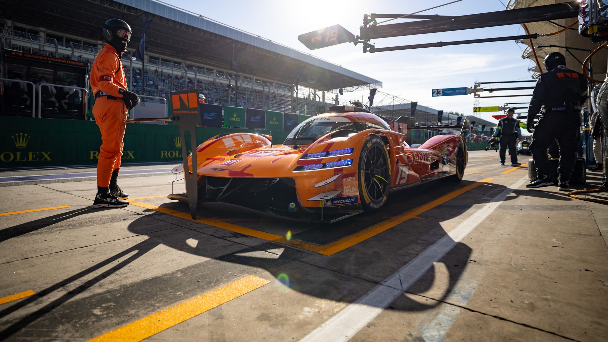 Genesis Magma Racing’s GRM-001 hypercar sits in the pit lane at Interlagos during a WEC session, surrounded by crew members and pit equipment under bright afternoon sunlight.