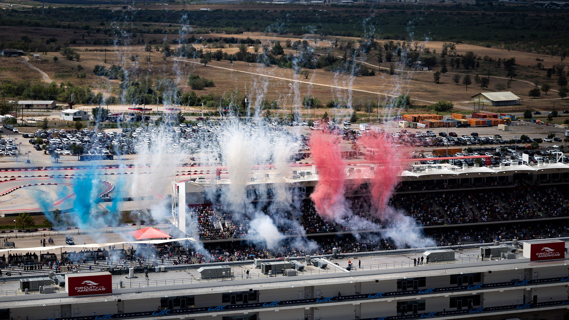 Red, white, and blue smoke fills the sky above the COTA grandstand during the Lone Star Le Mans weekend.