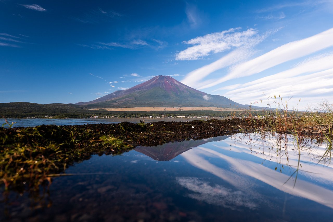 Mount Fuji reflected in the water beneath a bright blue sky.
