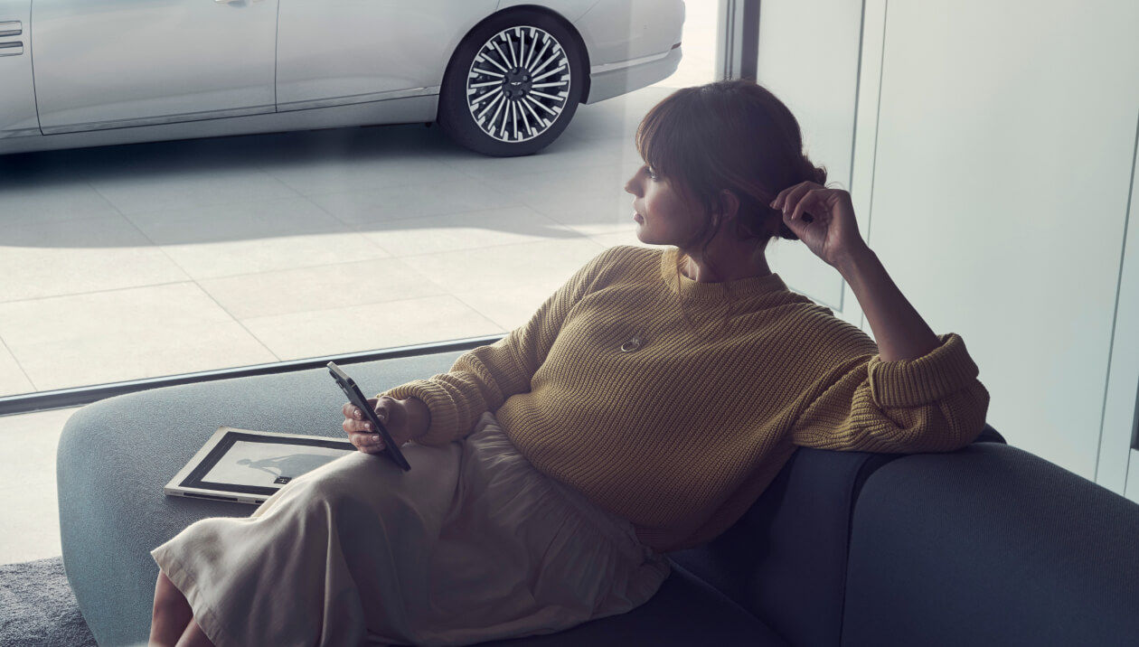 Woman on a sofa with a mobile phone in her hand looking out of the window