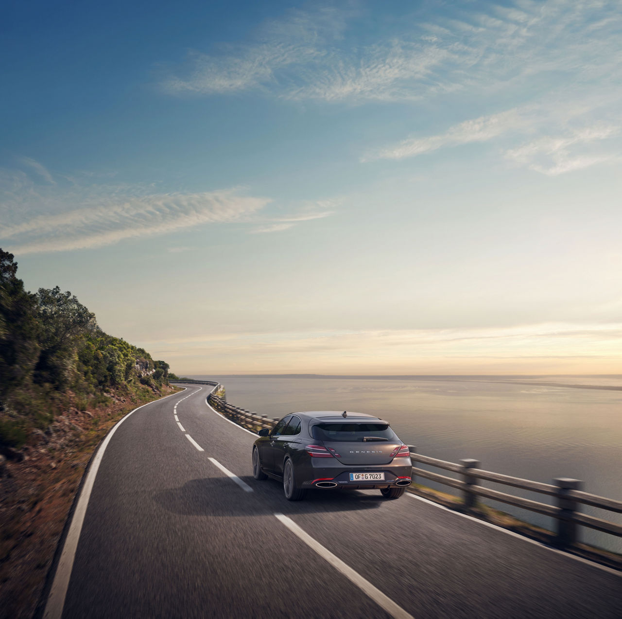 La Genesis G70 Shooting Brake grise roule sur une route près de la mer - vue arrière