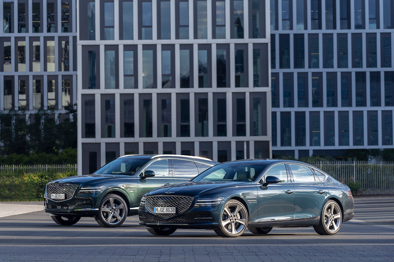 Genesis G80 bleu et GV80 vert à l'extérieur d'un bâtiment moderne