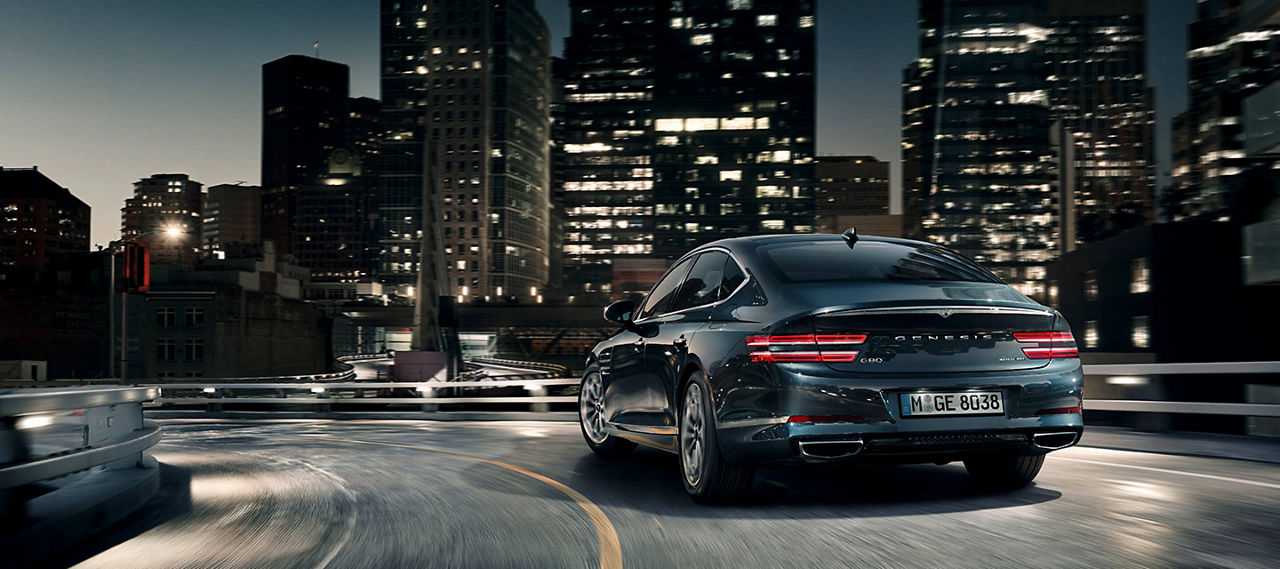 Genesis G80 sur l'autoroute en soirée  Skyline - vue arrière