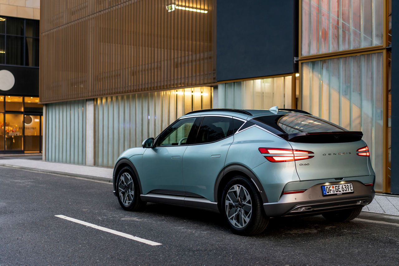 Genesis GV60 in mint colour on a road with containers in the background