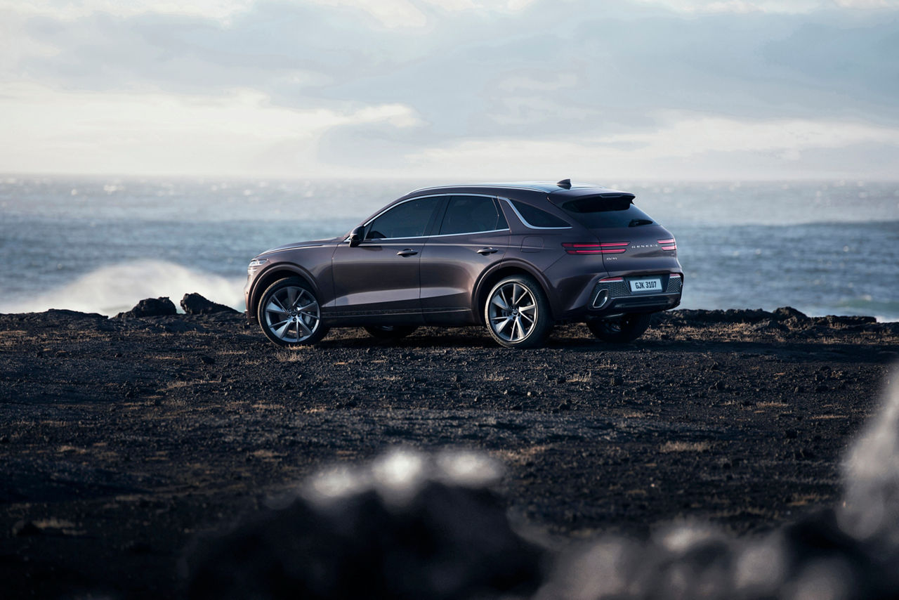 Vue latérale du Genesis GV70 Burgundy sur la côte islandaise avec la mer en arrière-plan