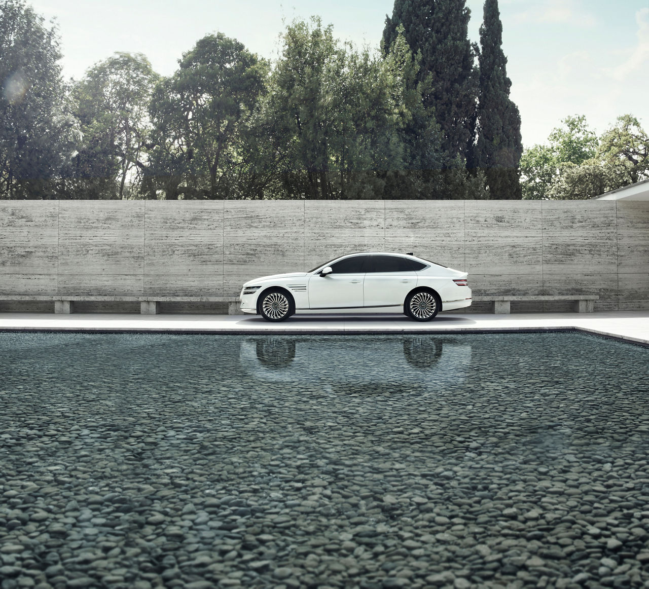 White Genesis G80 from the side in front of a wall next to a pool