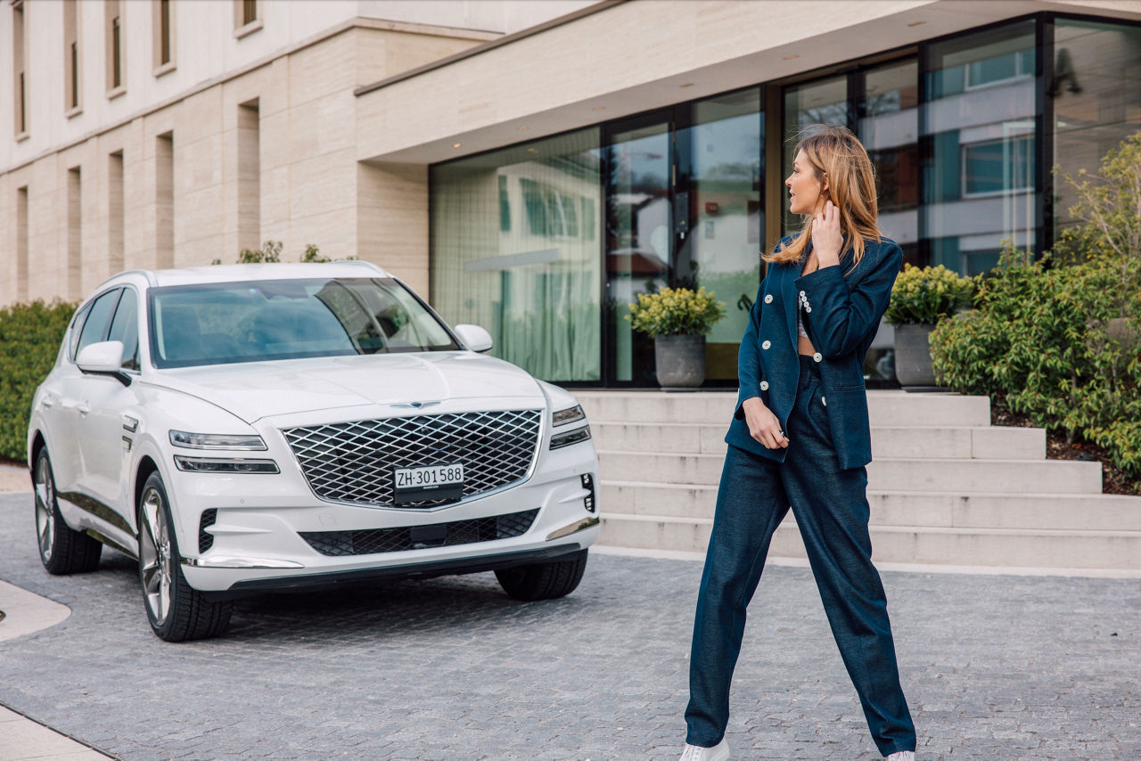 Un GV80 blanc et une femme devant un hôtel lors des Genesis Experience Days 2022