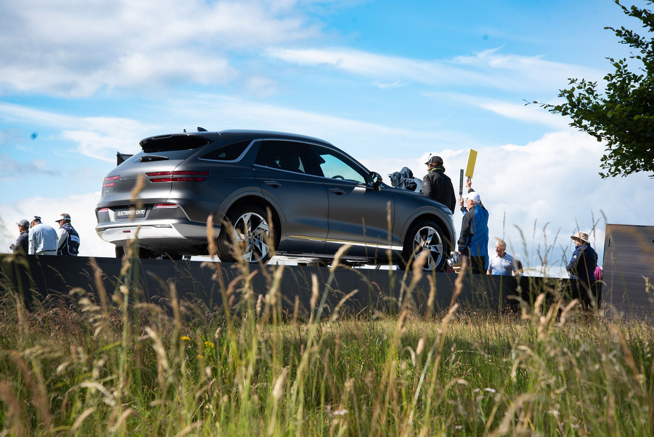 Genesis GV70 auf einem Golfplatz mit Menschen drumherum