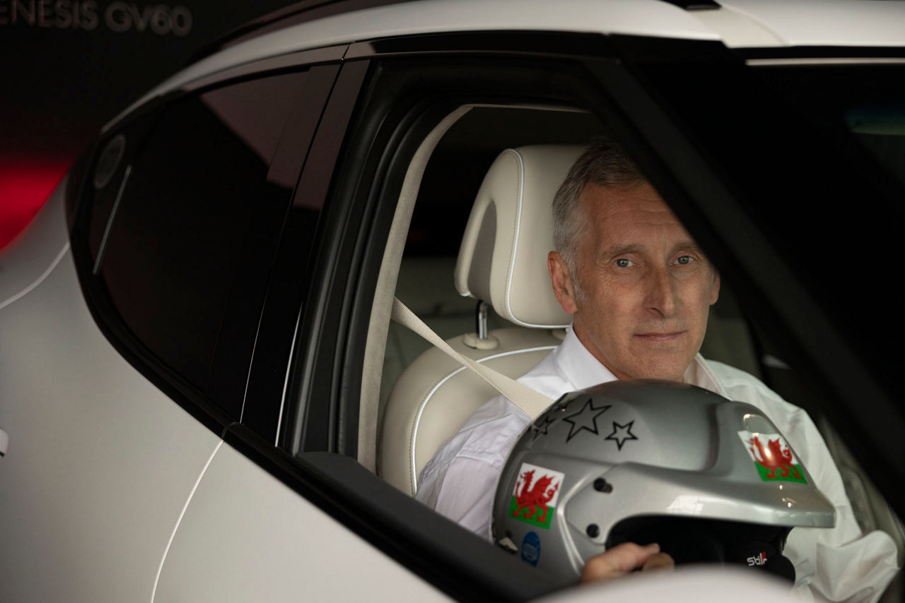 Man in the passenger seat of a car with a helmet in his hand