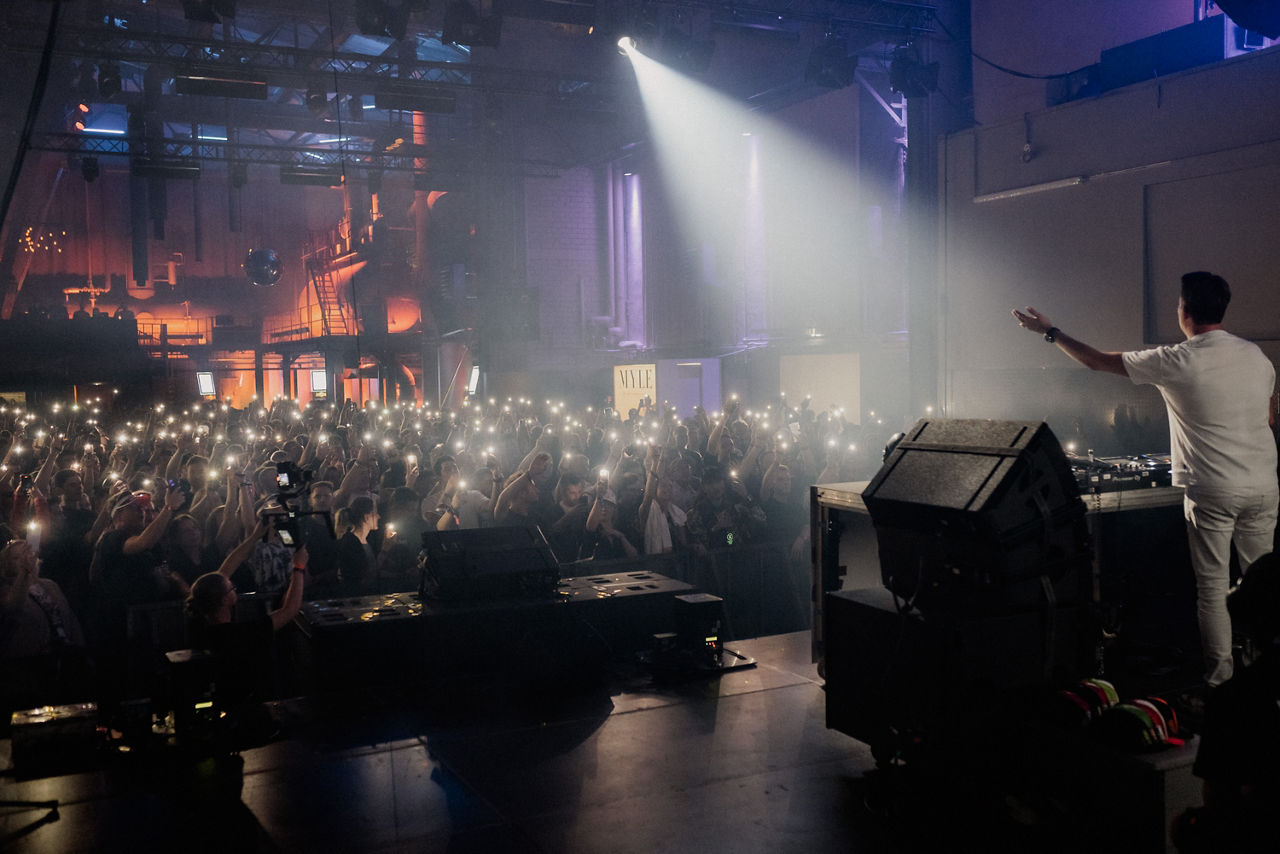 DJ on stage in front of an audience at the Genesis Myle Festival