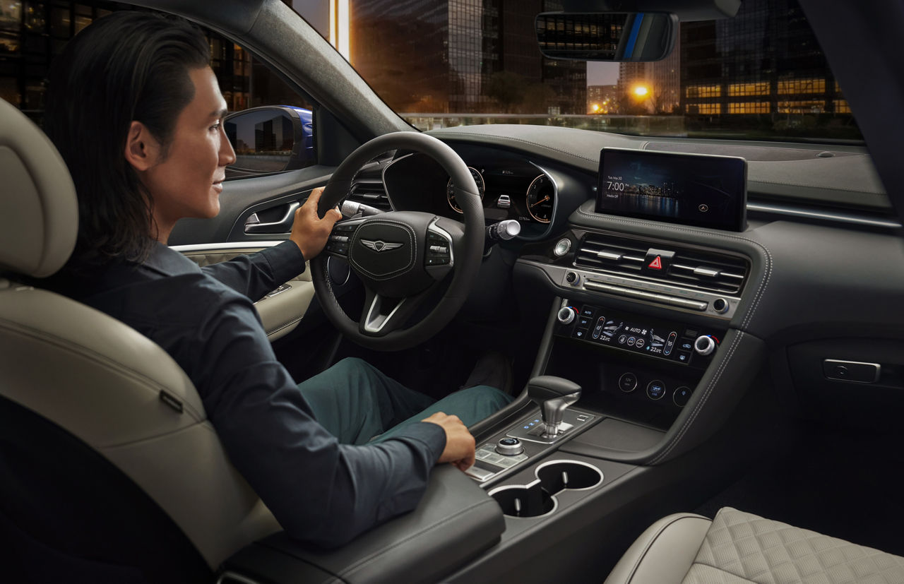 Man at the wheel of the Genesis G70 looks at the display in the centre