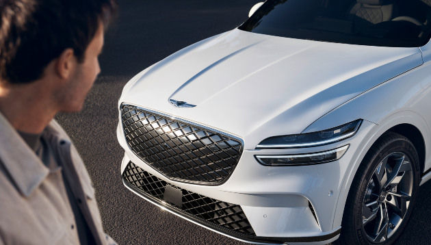 Un homme regarde l'avant d'une voiture Genesis blanche